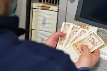 iza šaltera, novčanice od 100 KM u ruci